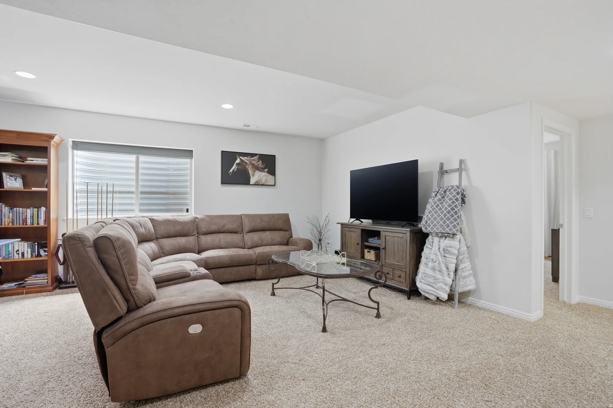 Spacious living area featuring light-toned carpeting and recessed lighting