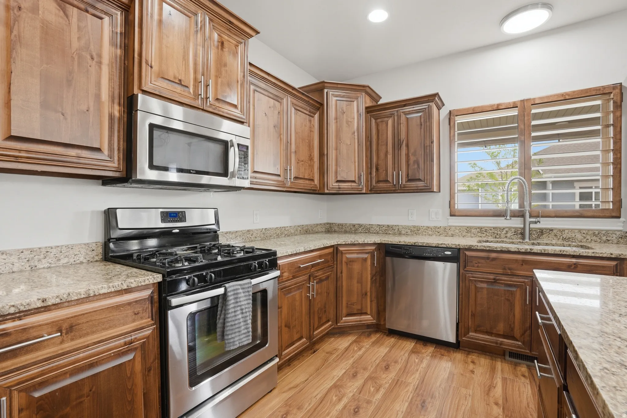 Kitchen featuring wood-finish flooring, ample wood cabinetry, and stone countertops