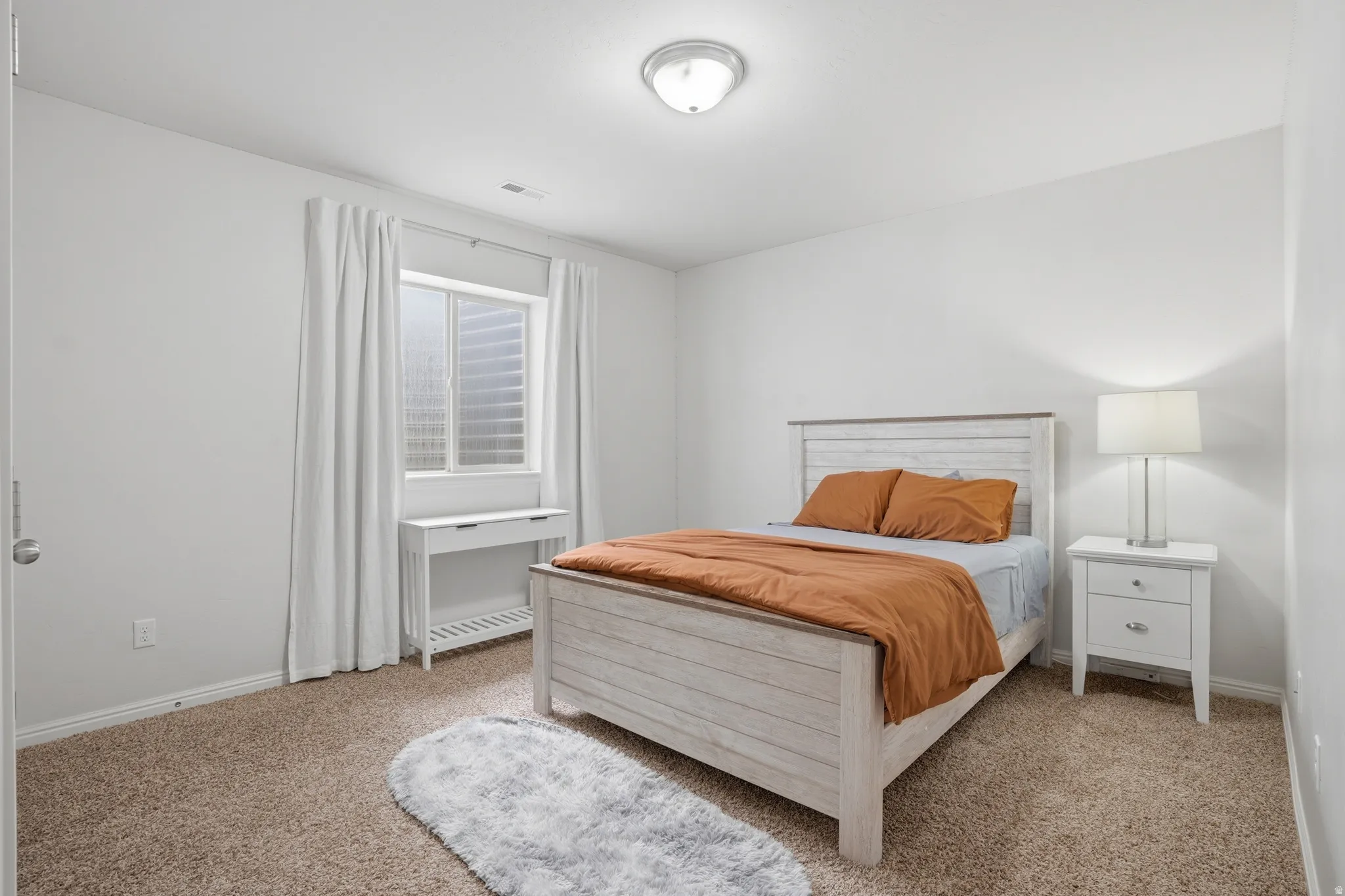 Bedroom featuring light tan carpet and white walls