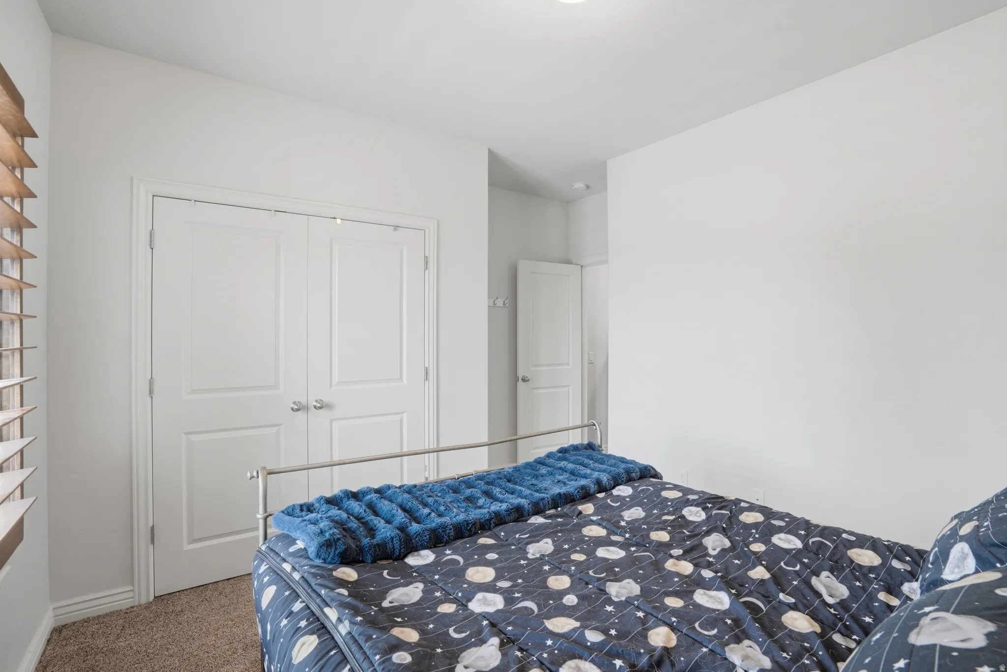Bedroom featuring light brown carpet flooring, white walls, and a white paneled door