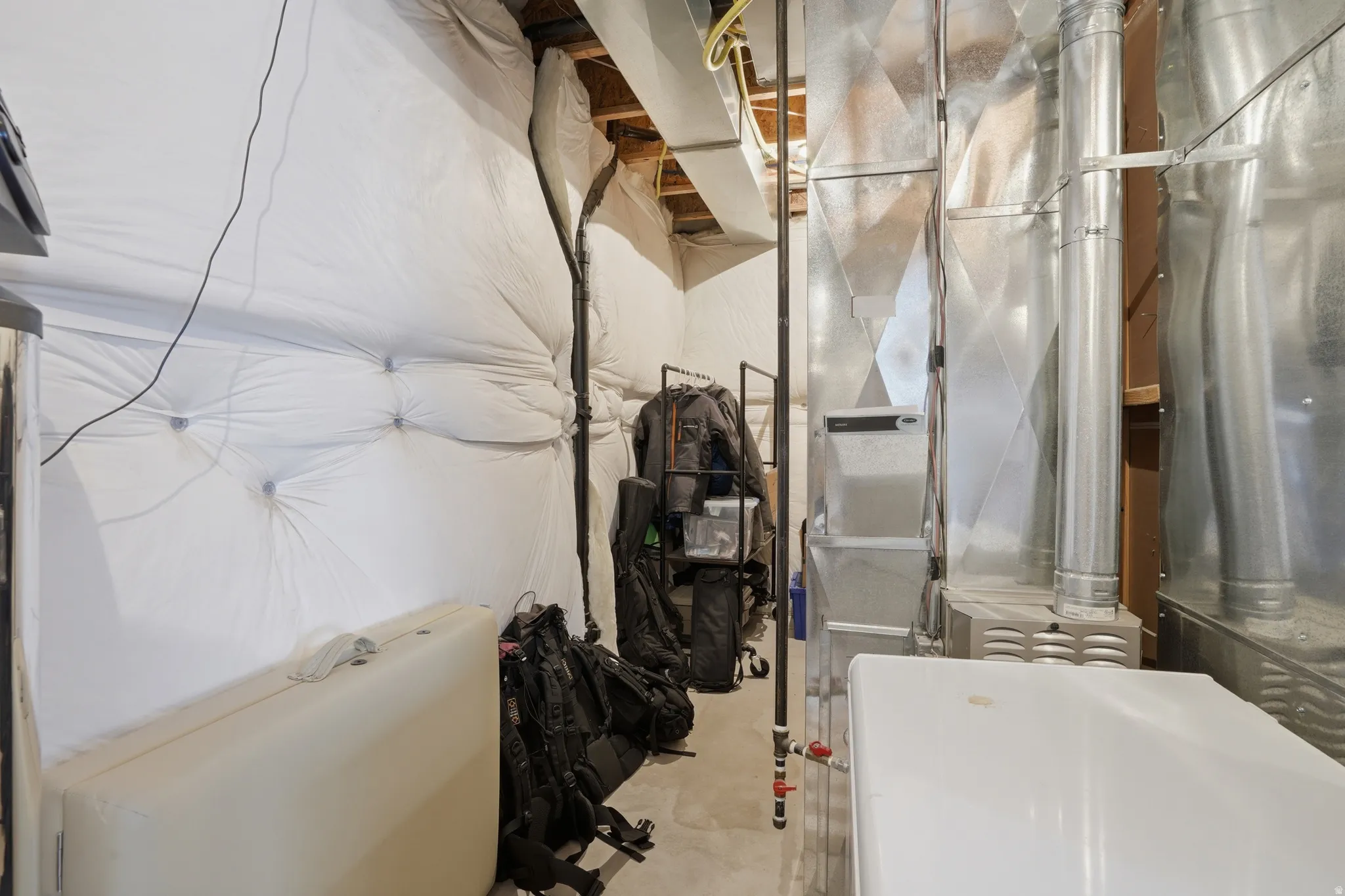 Utility space featuring exposed ductwork, a furnace system, and concrete flooring