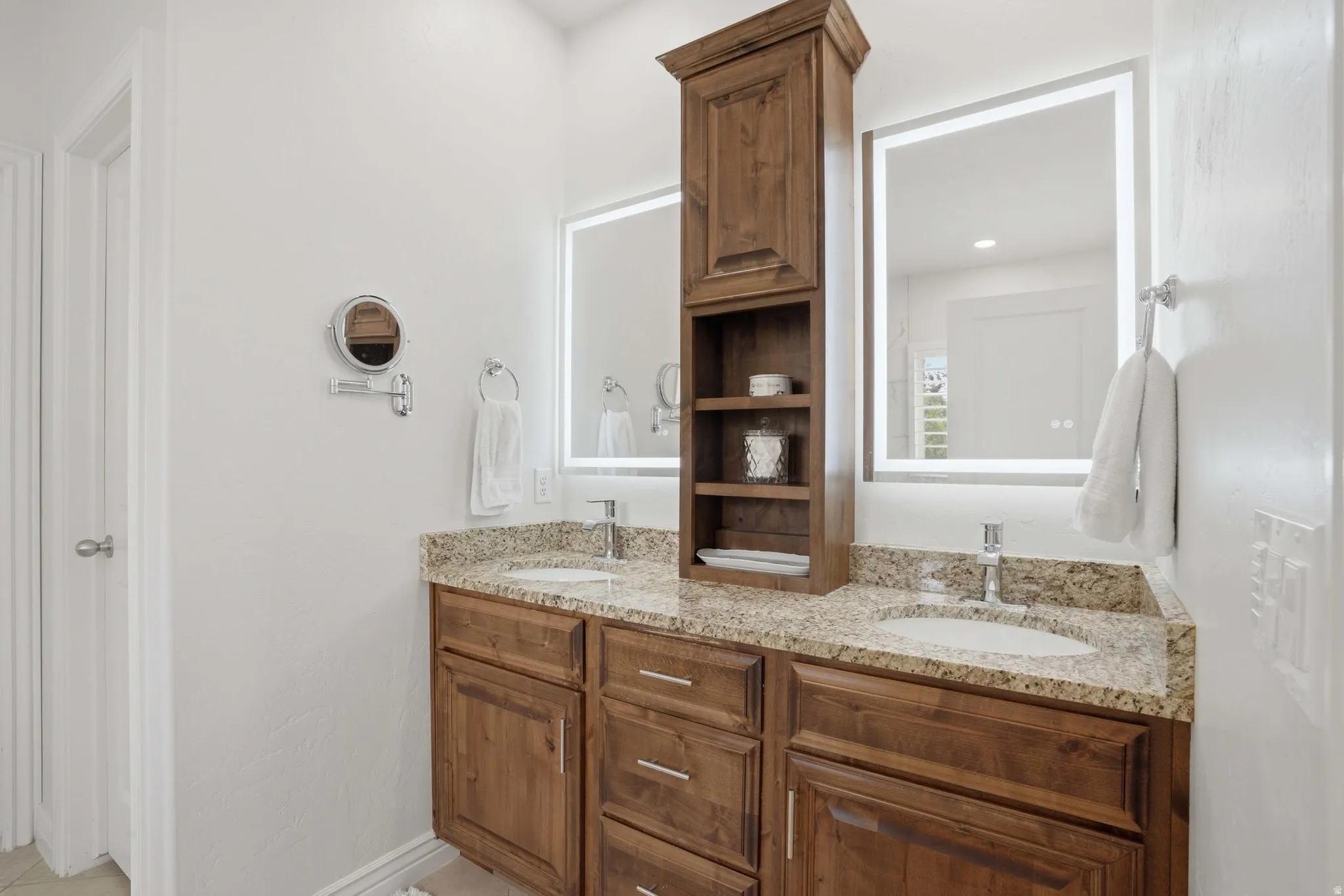 Dual vanity with a granite countertop, integrated sinks, and wood-finish cabinetry