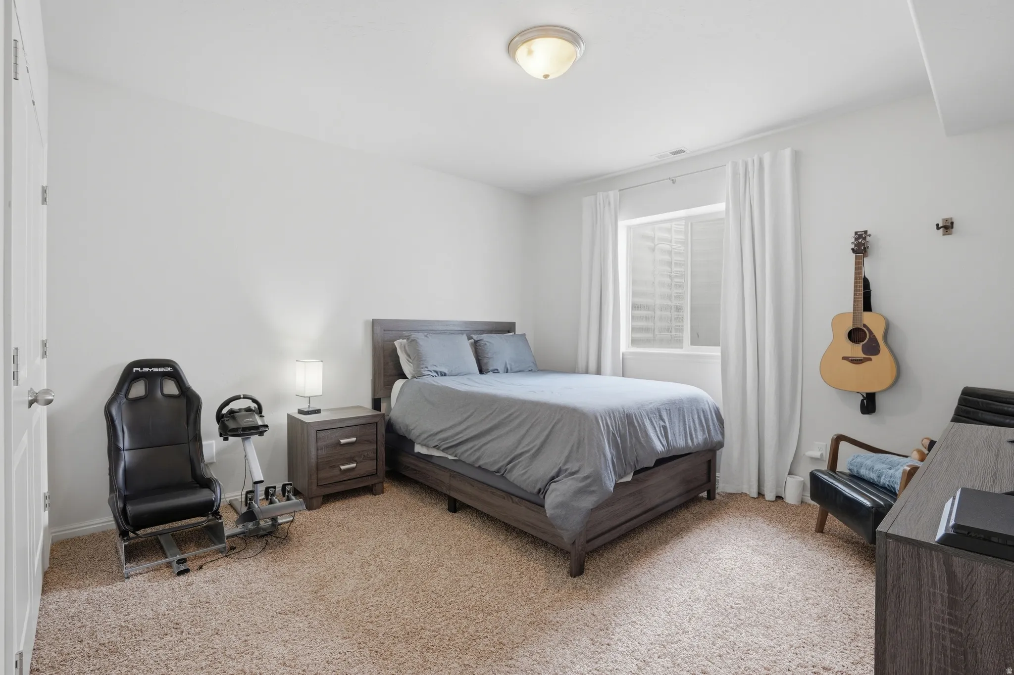 Carpeted room with a window, white walls, and a ceiling-mounted light fixture