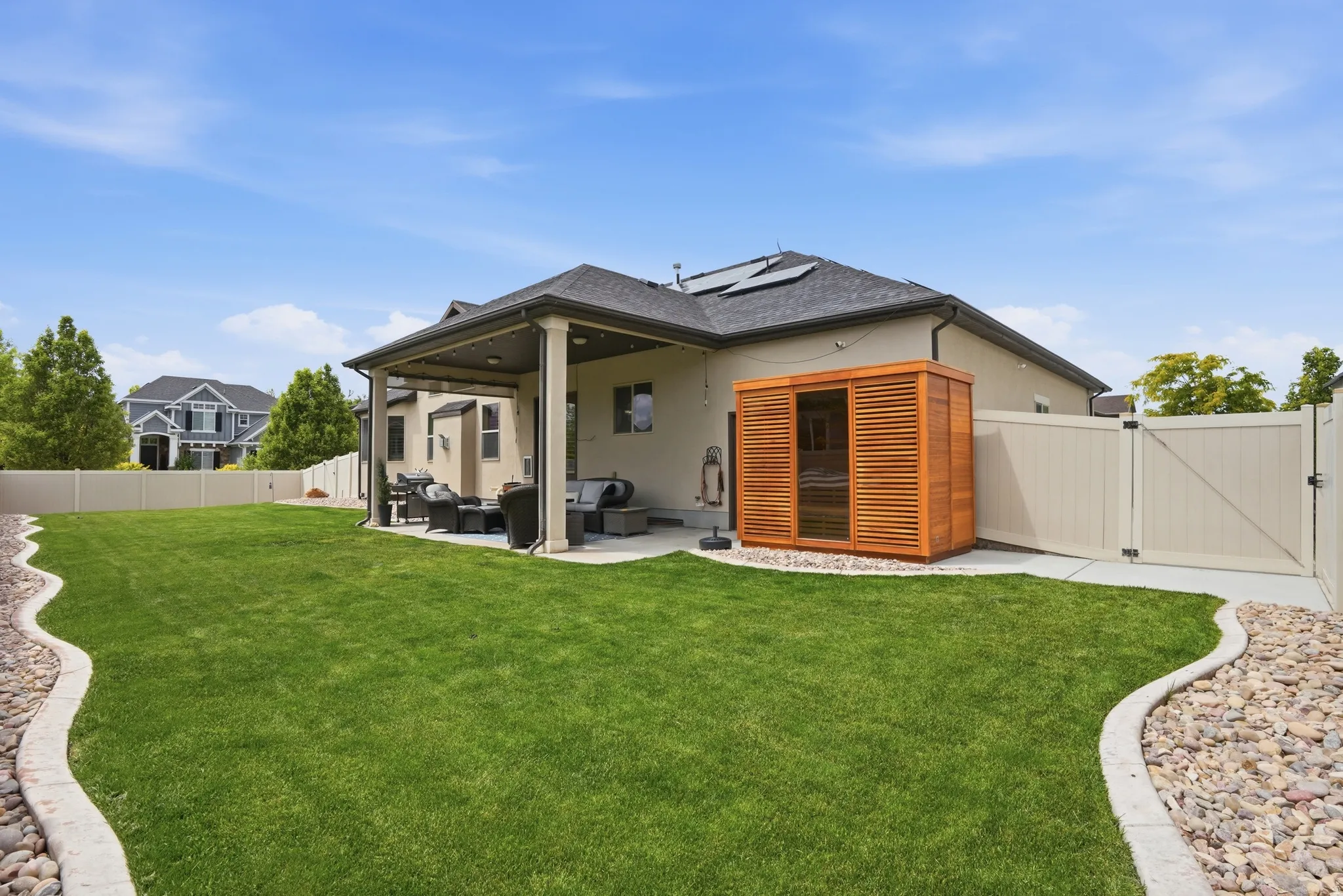 Spacious backyard featuring a manicured lawn, an outdoor sauna (optional), a covered patio, a concrete patio extension, and a privacy fence