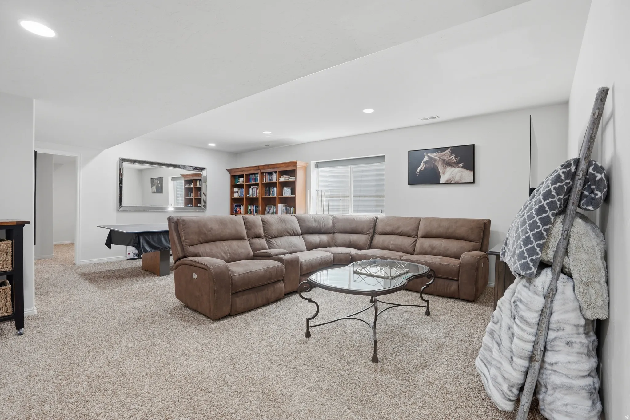 Spacious room featuring neutral carpeting, recessed lighting, and a large window with blinds