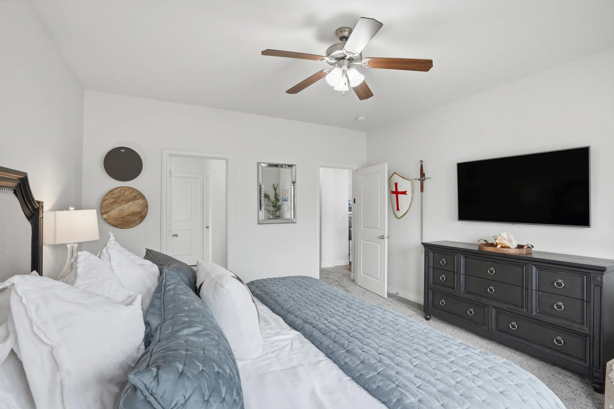Master bedroom featuring light neutral wall paint, a ceiling fan with integrated lighting, two panel doors, and carpet flooring