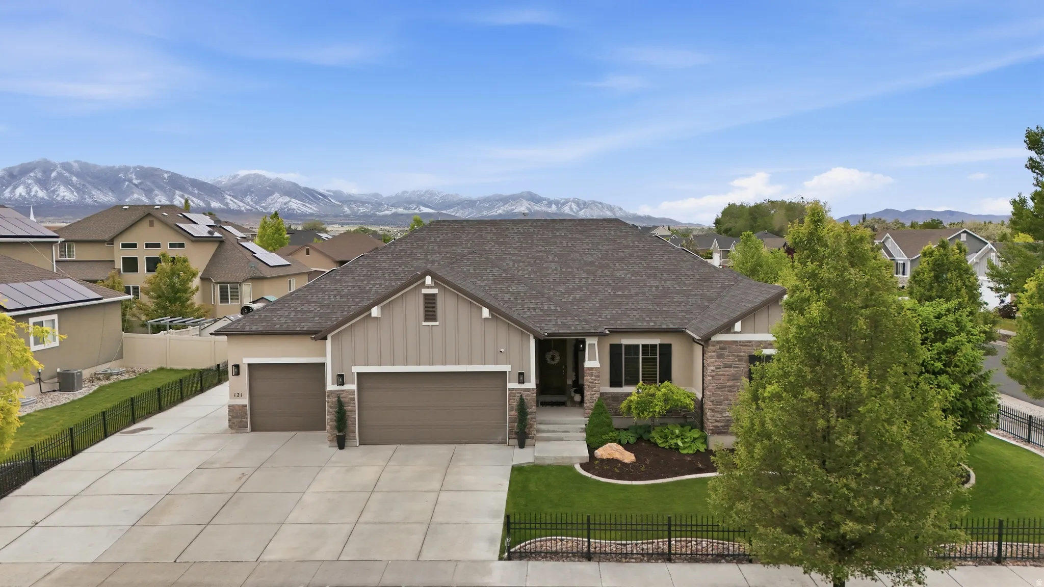Ranch-style residence featuring a prominent two-car garage, stone and siding exterior, and a manicured front lawn