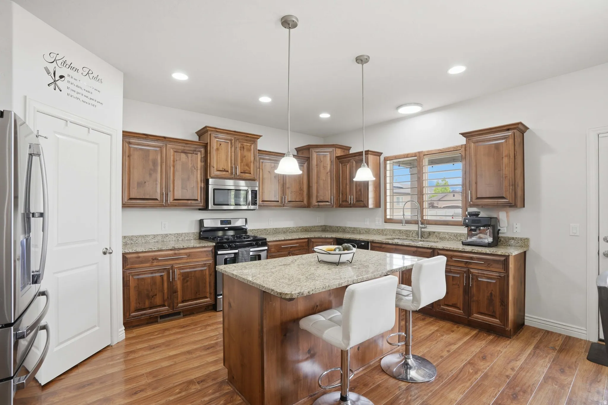 Kitchen featuring wood-finish flooring, granite countertops, and rich wood cabinetry