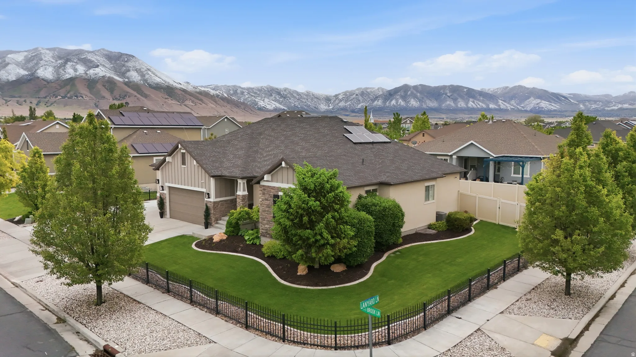 Single-story residence featuring a stone and siding exterior, a multi-car garage, and a fenced front yard with mature landscaping