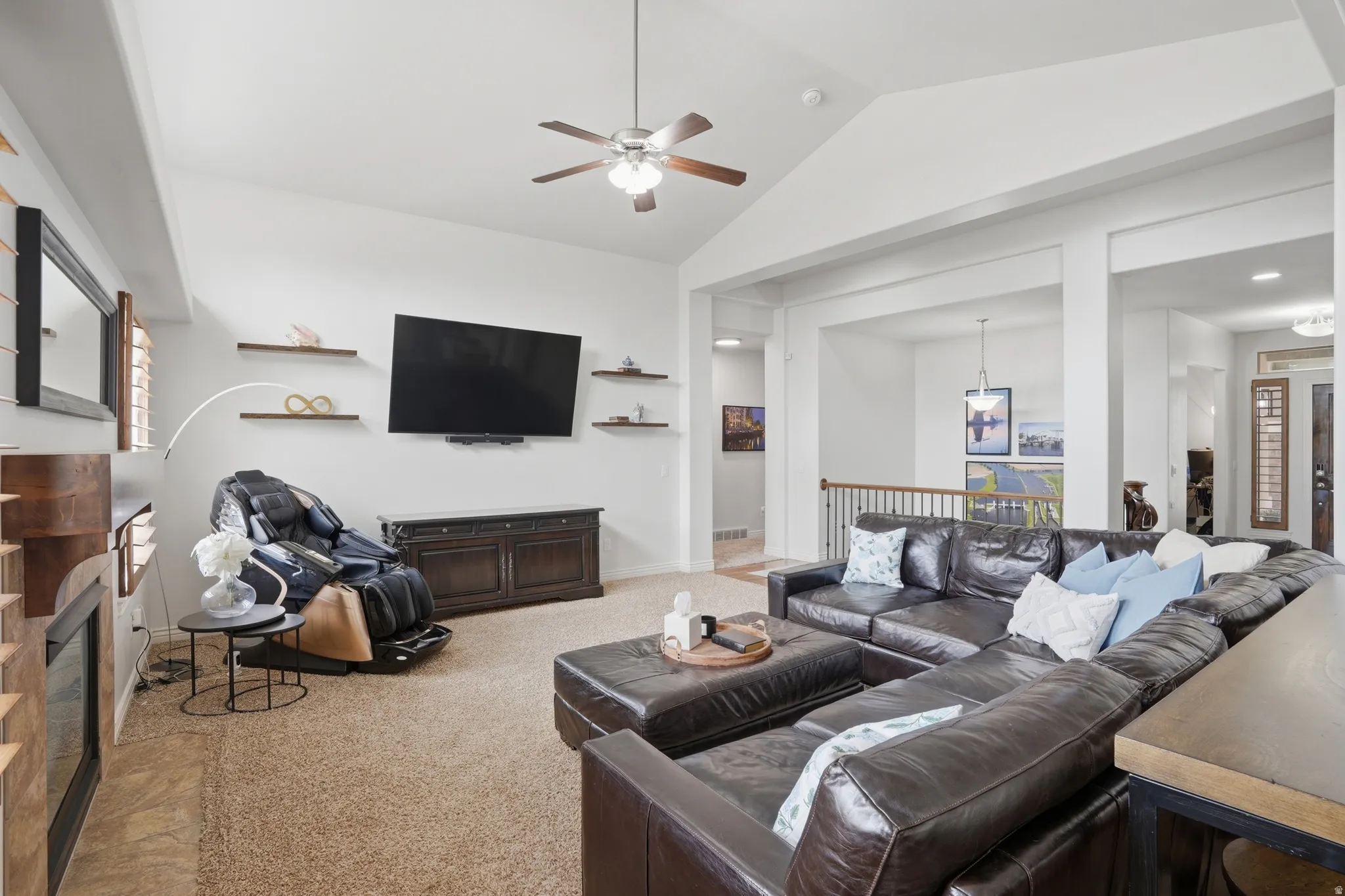 Spacious living area featuring vaulted ceilings, a ceiling fan, and built-in decorative shelving