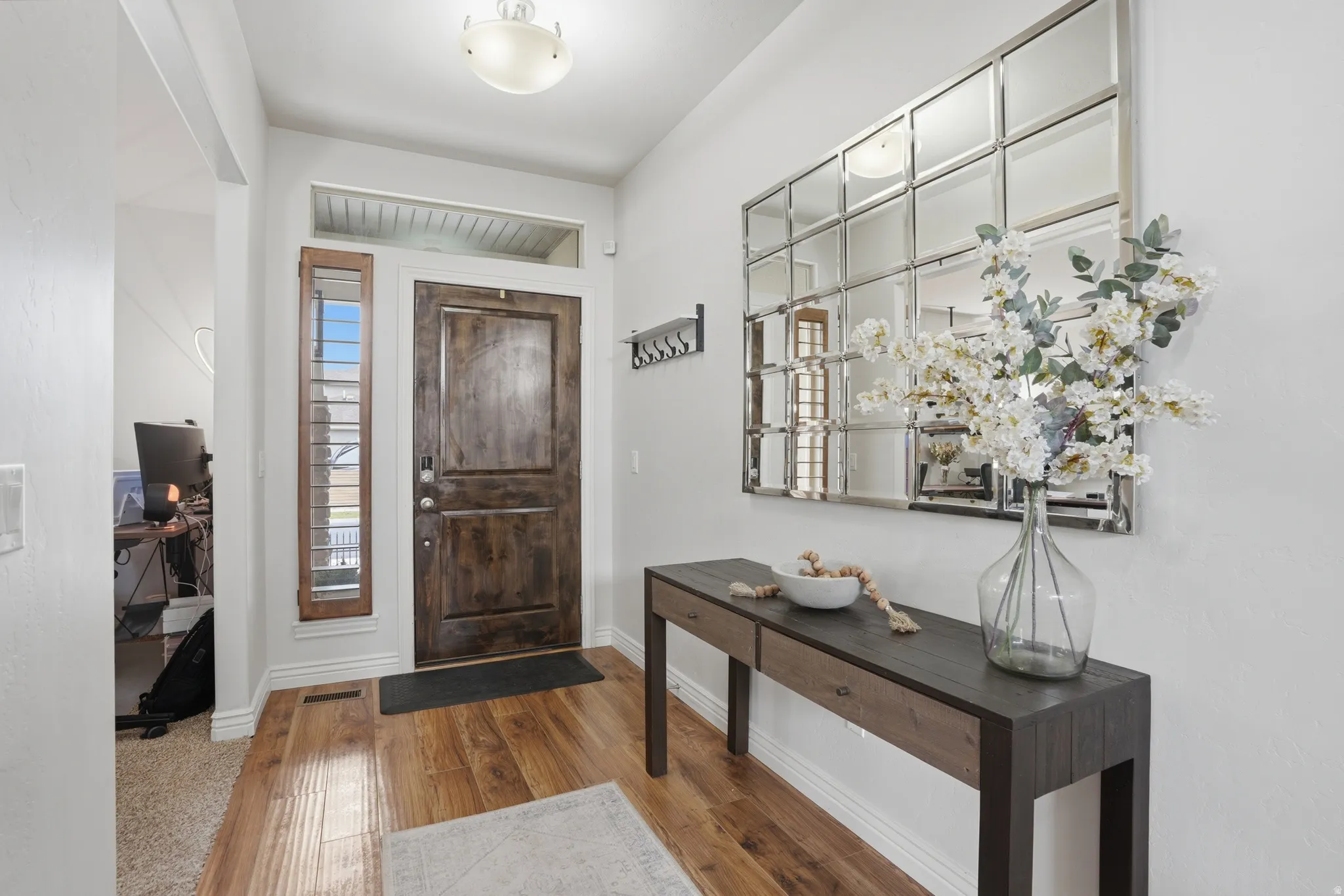 Entryway featuring rich wood-finish flooring and a substantial dark wood entry door with a multi-pane sidelight
