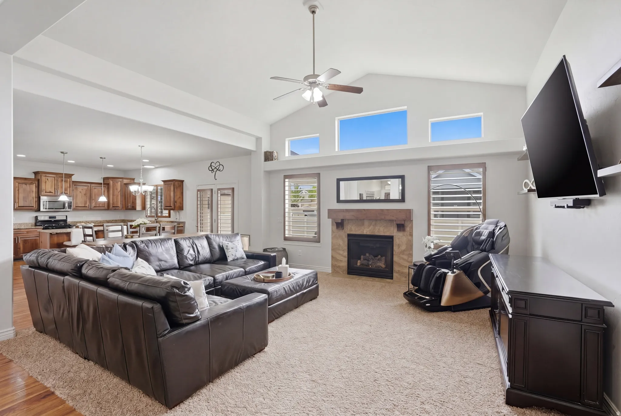 Open-concept living area featuring vaulted ceilings, a ceiling fan, and high transom windows