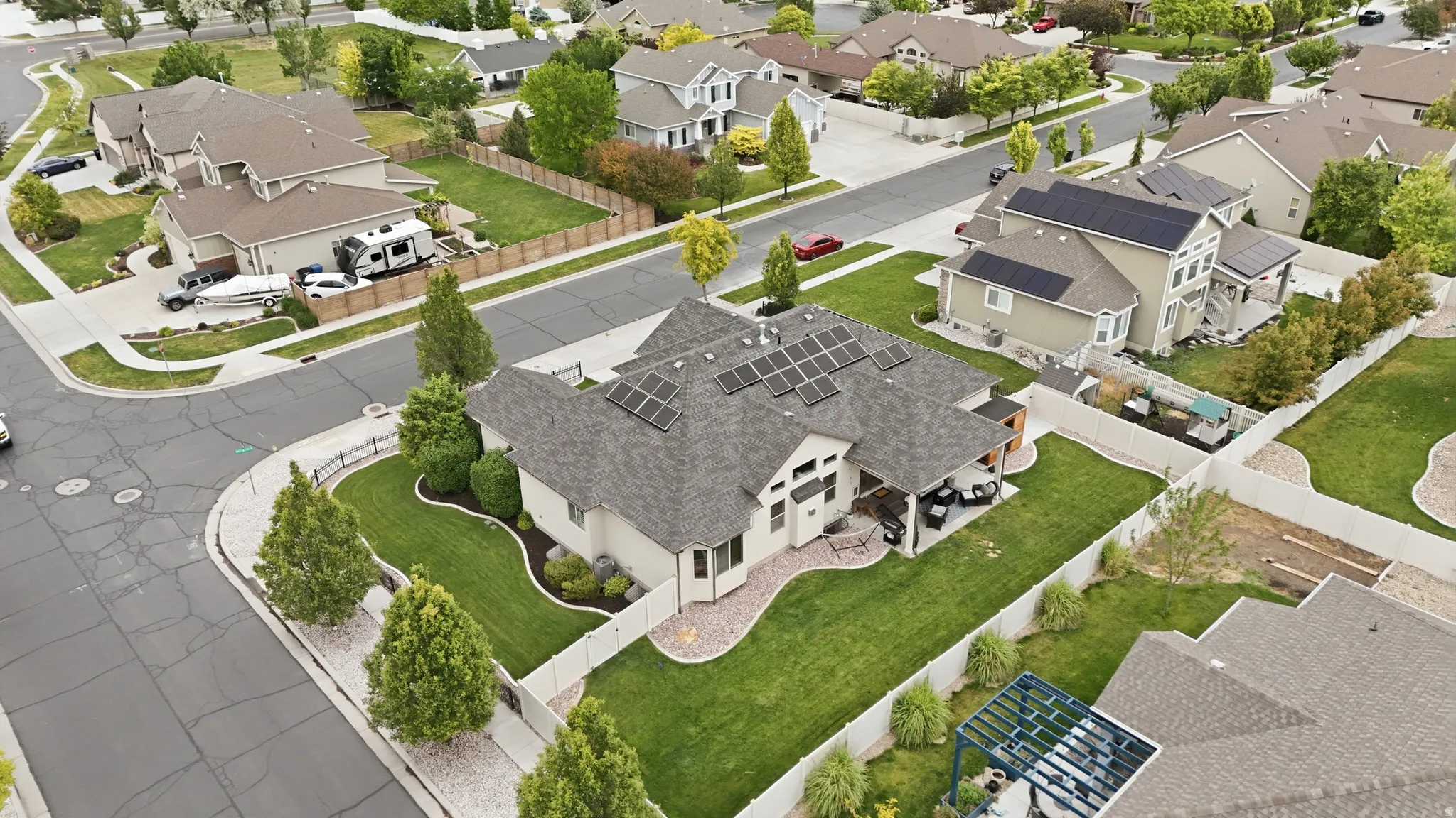 Contemporary residential property on a corner lot featuring a dark shingle roof with solar panels