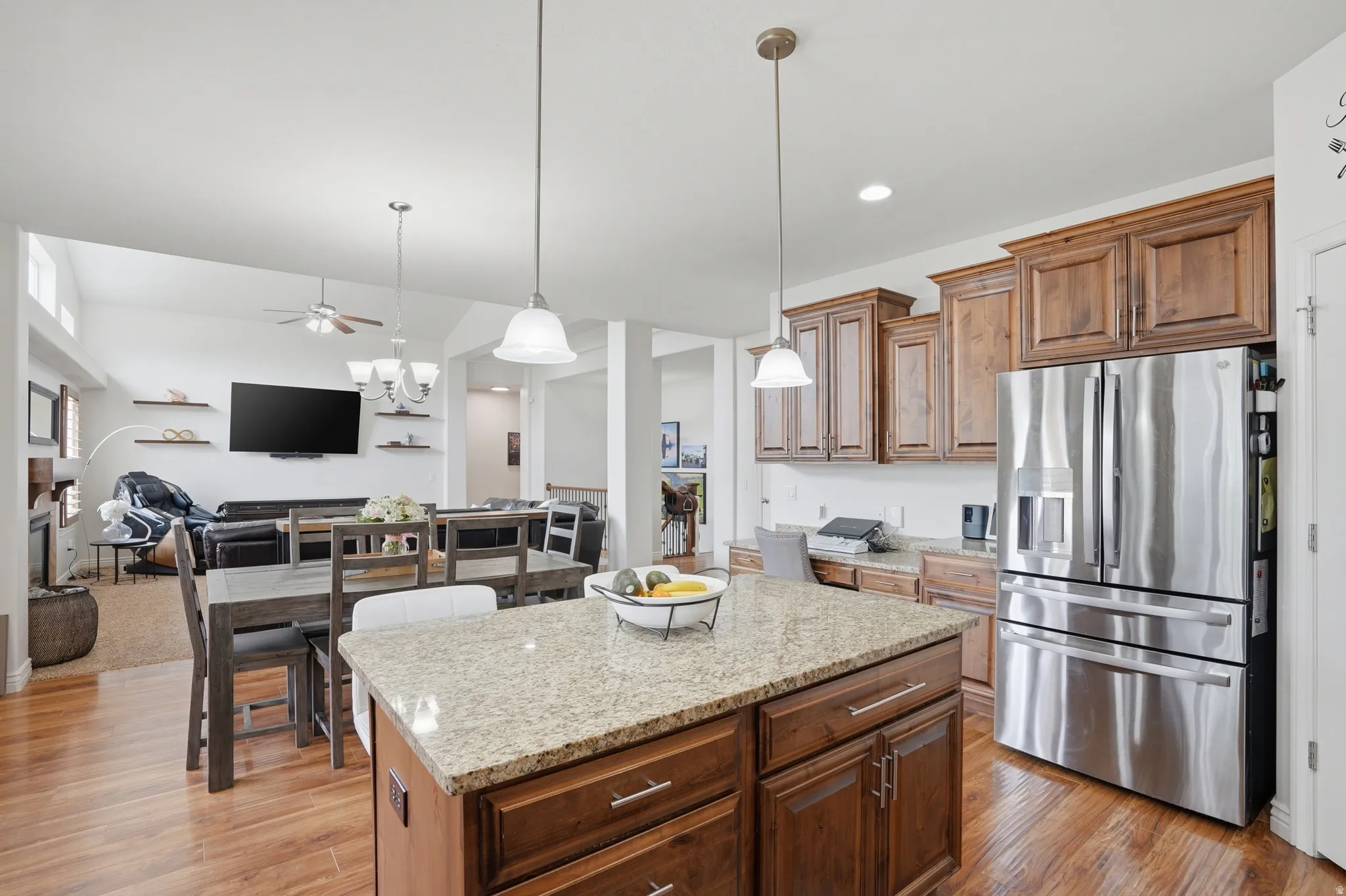 Kitchen island with granite countertop, wood-finish flooring, and pendant lighting