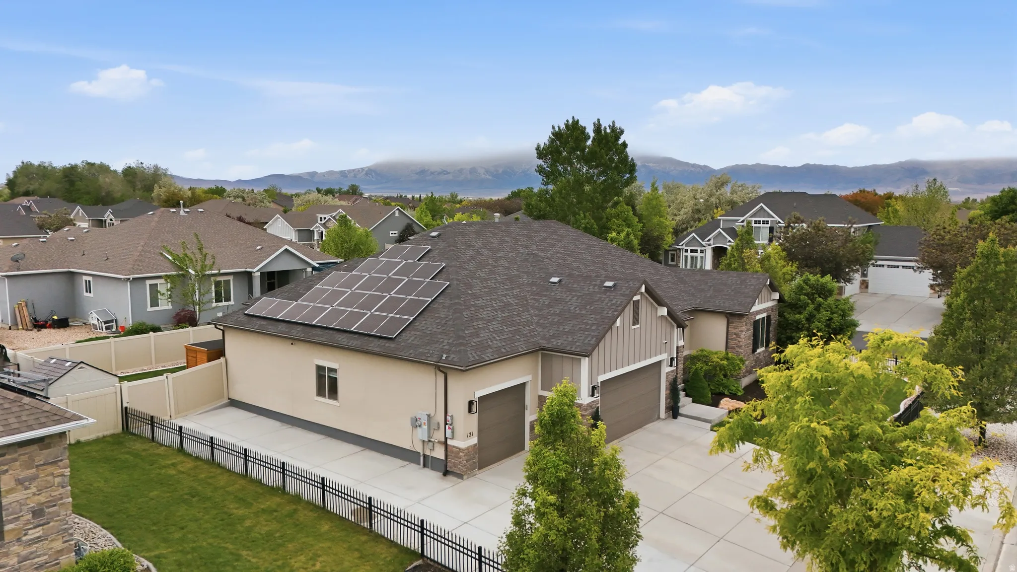 Contemporary architecture featuring a multi-tone exterior, attached multi-car garage with panel doors, and solar panels