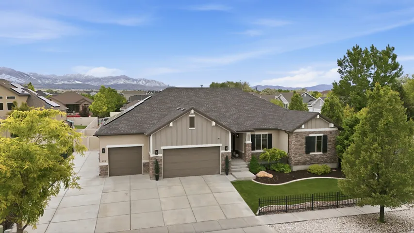 Residence featuring a combination of stone and siding exterior, a multi-car garage, and a landscaped yard with fence