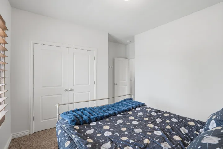 Bedroom featuring light brown carpet flooring, white walls, and a white paneled door