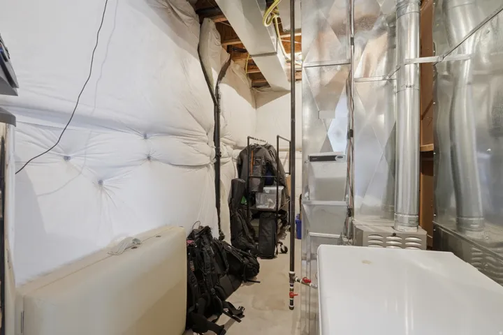Utility space featuring exposed ductwork, a furnace system, and concrete flooring