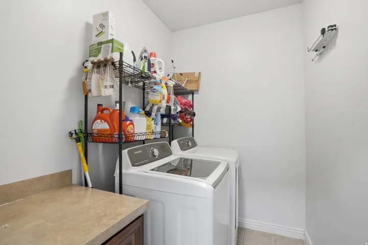 Dedicated laundry area featuring a countertop with storage below, and tiled flooring