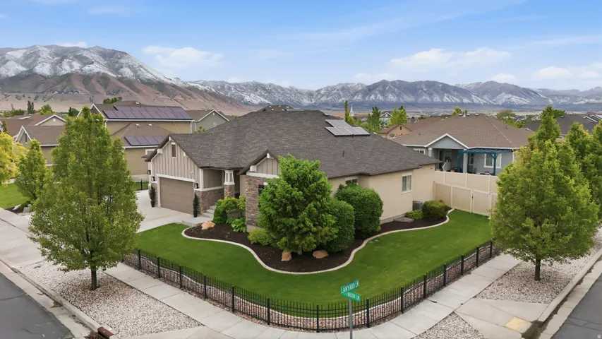 Single-story residence featuring a stone and siding exterior, a multi-car garage, and a fenced front yard with mature landscaping