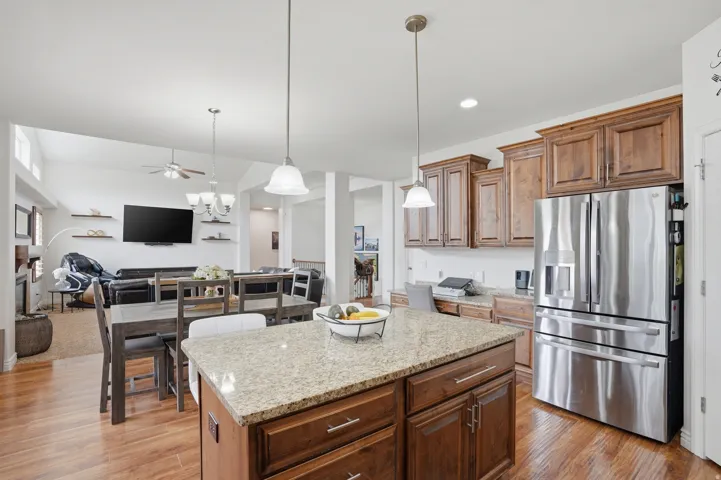 Kitchen island with granite countertop, wood-finish flooring, and pendant lighting