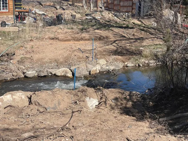 Natural creek with rock-lined banks and surrounding undeveloped terrain