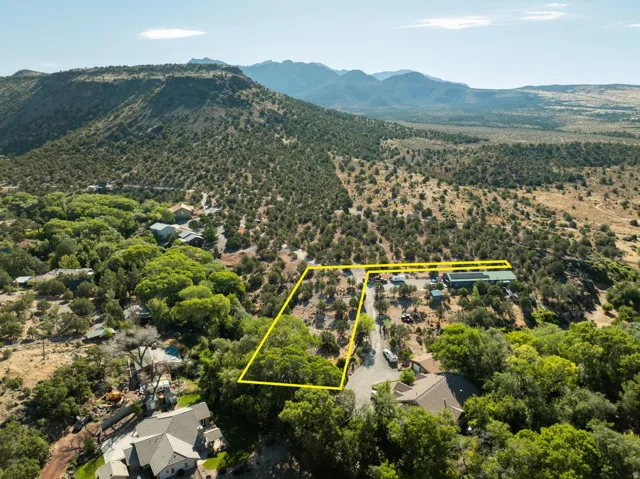 Expansive land parcel featuring natural terrain, mature trees, and a distant mountainous backdrop