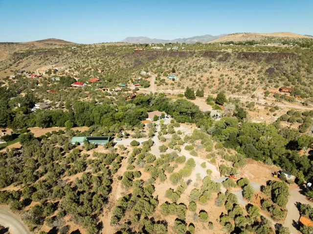 Hillside landscape featuring scattered residential structures and diverse vegetation