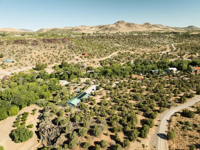 Expansive property featuring a green-roofed structure with solar panels, surrounded by abundant desert flora and mature trees