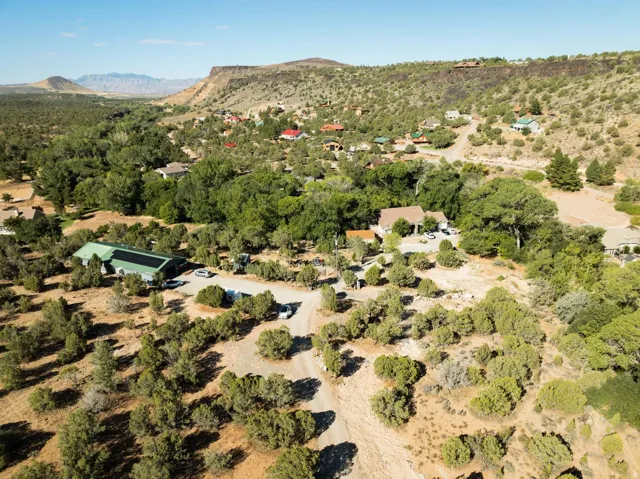Expansive rural property featuring a green-roofed structure with solar panels, surrounded by native trees and scrubland