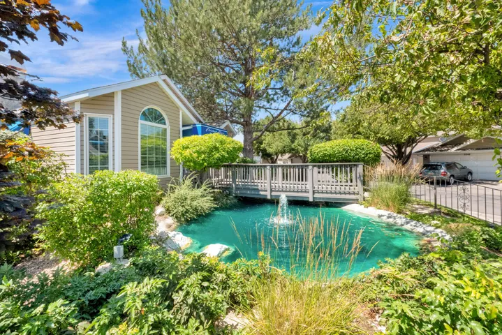 Exterior siding with an arched window, a wooden bridge, and a water feature with a fountain