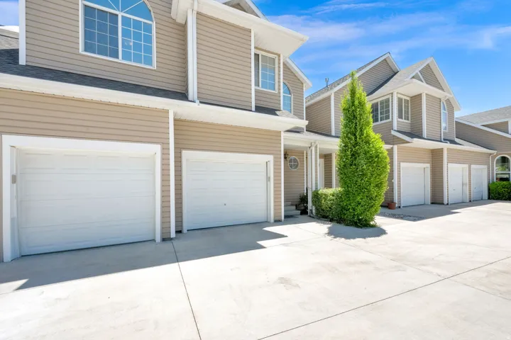 Exterior featuring beige siding, white trim, arched windows, multiple attached garages, and concrete driveways