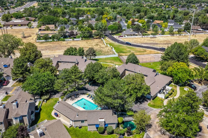 Outdoor pool with surrounding patio, mature landscaping, and multi-unit residential buildings