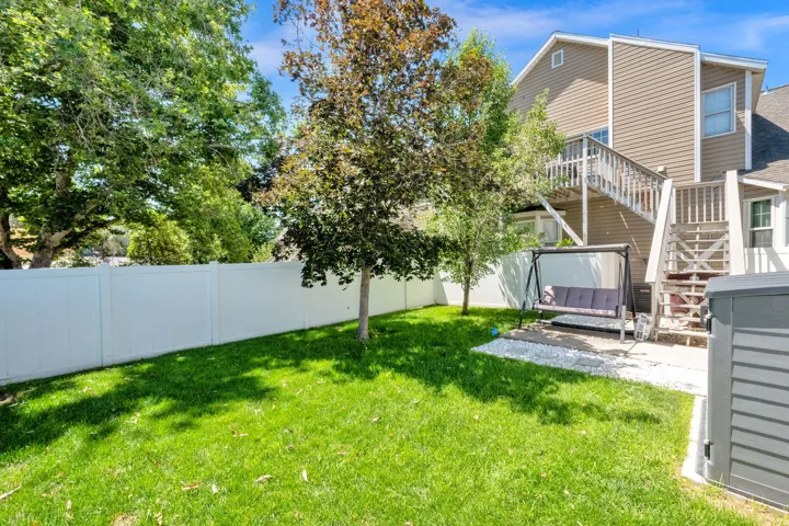 Expansive green lawn with a white privacy fence