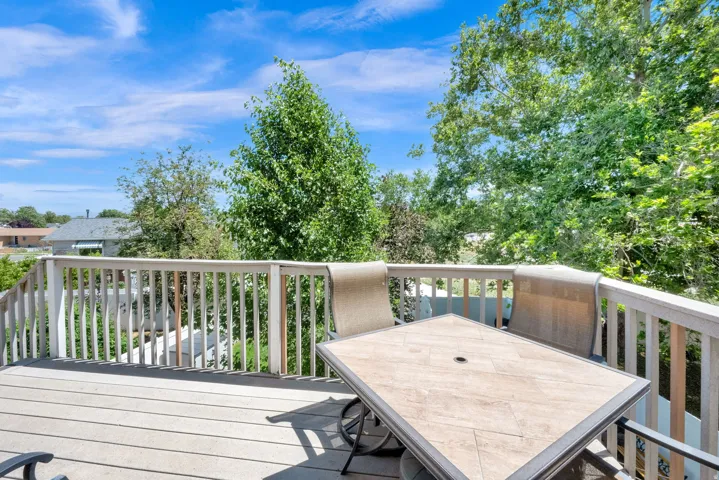 Outdoor deck featuring composite flooring, white railing, and mature trees