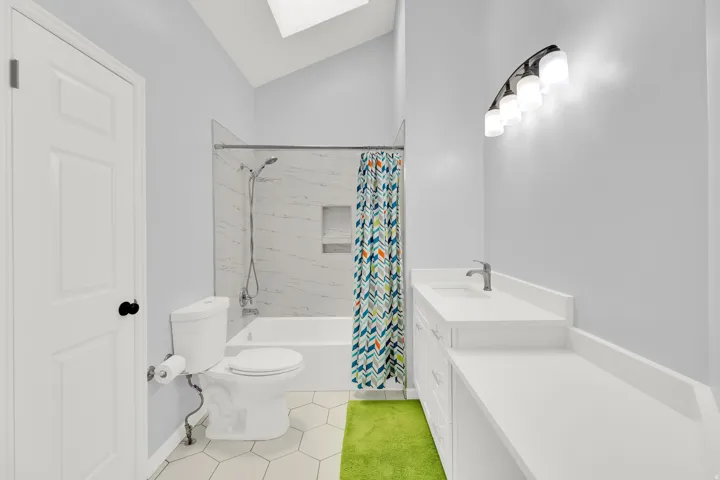 Bathroom featuring a white vanity with an integrated sink, a white countertop, and a four-light fixture