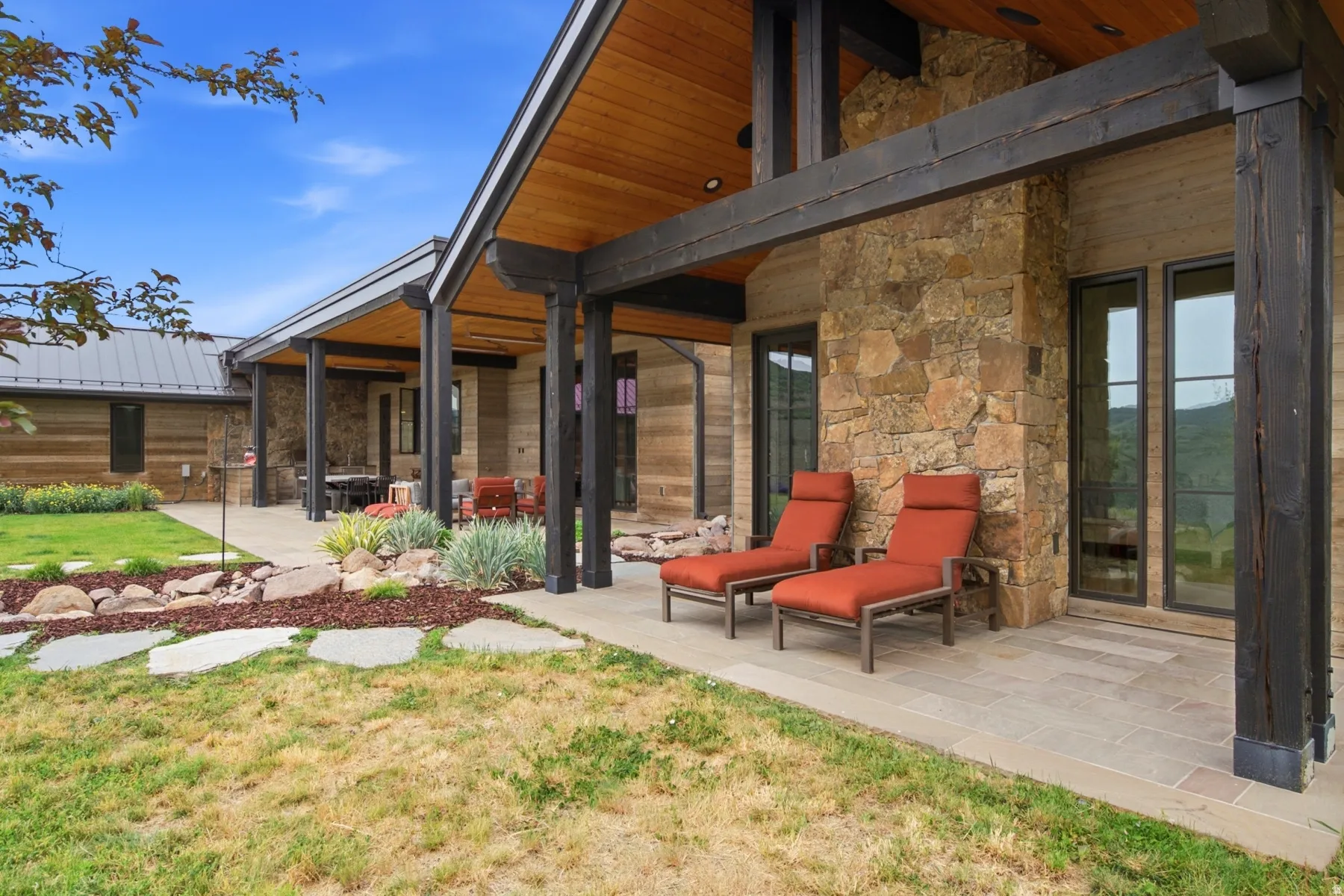 Expansive covered patio featuring a stone facade, wood-finish ceiling, and exposed wood beams