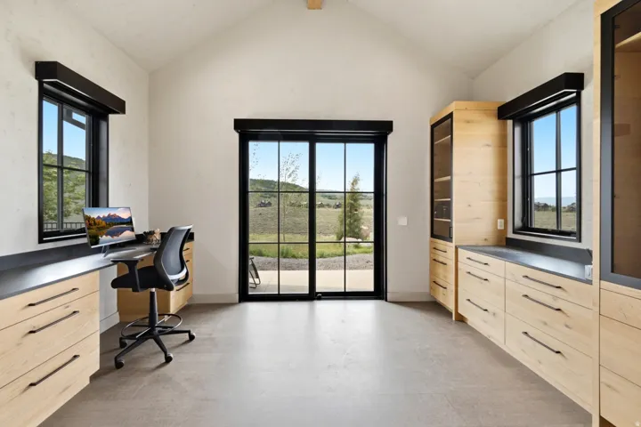 Vaulted ceiling room featuring light wood-finish cabinetry with dark hardware and countertops