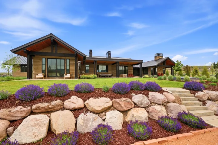 Expansive landscaped yard featuring a rock retaining wall with purple flowering plants and stone steps