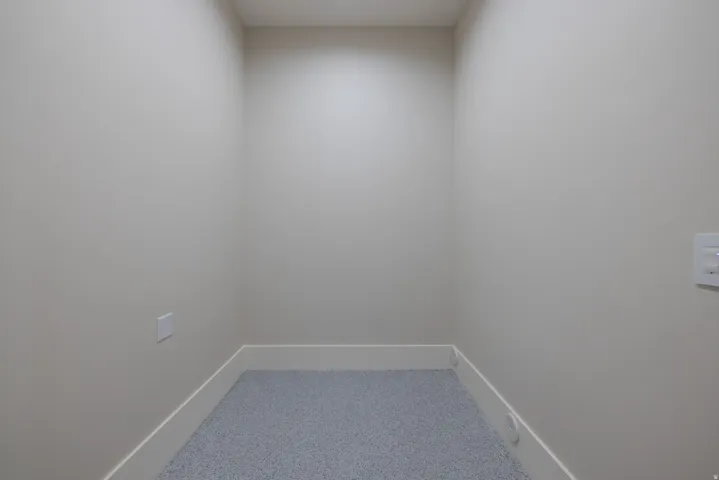 Recessed alcove with light neutral wall tones, white baseboards, and speckled flooring