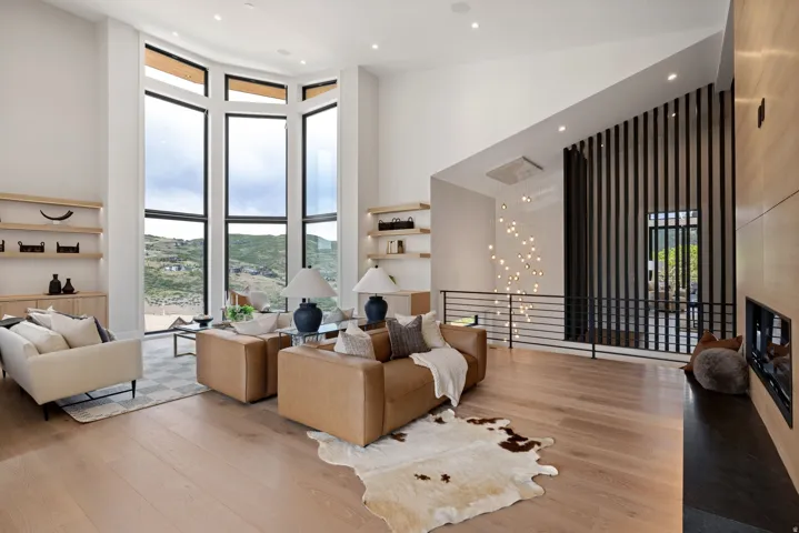 Vaulted living area featuring expansive floor-to-ceiling windows, light wood-finish flooring, and built-in shelving