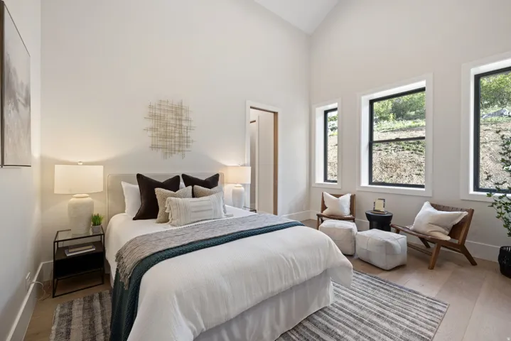 Room featuring vaulted ceilings, light wood-finish flooring, and multiple windows with dark frames