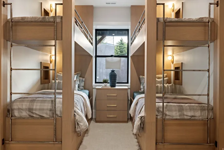 Built-in bunk beds with integrated wooden ladders and individual sconce lighting