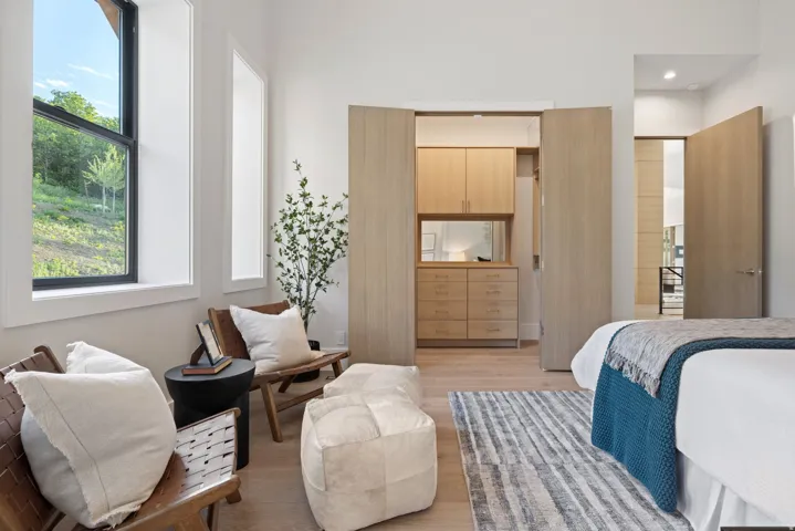 Interior room featuring two large windows, light wood-finish flooring, and a built-in closet system with cabinetry and drawers