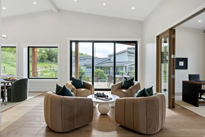 Vaulted ceilings define this open-concept room featuring wood-finish flooring, recessed lighting, and large windows with black frames