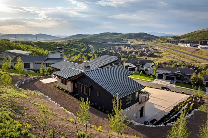 Modern mountain home featuring dark siding, stone accents, and a metal roof