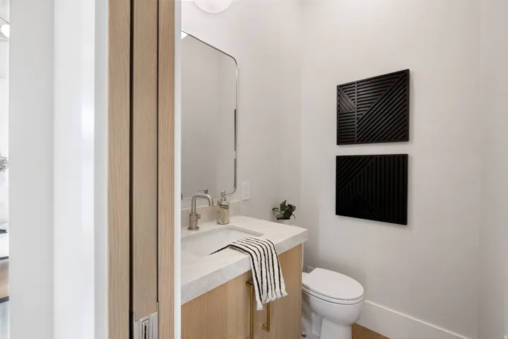 Powder room featuring a light wood-finish vanity with a light-colored countertop and undermount sink