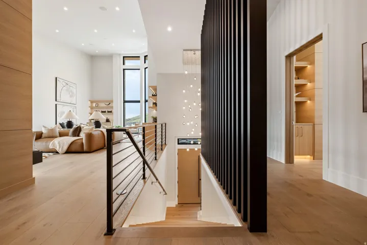 Open concept interior featuring light wood-finish flooring, a contemporary staircase with metal railings, high ceilings, recessed lighting, and a large window