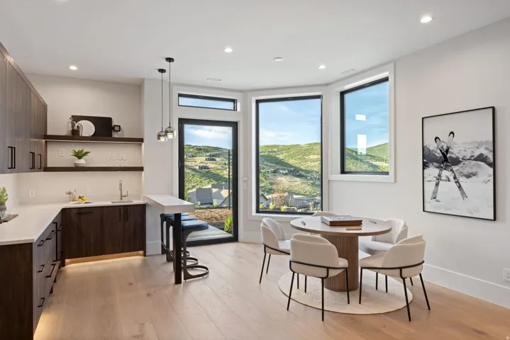 Light wood-finish flooring complements the contemporary built-in wet bar featuring dark wood-finish cabinetry, white countertops, and a stainless steel sink