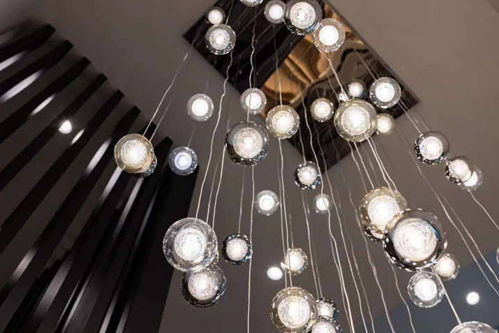 Multi-tiered chandelier featuring numerous suspended glass orbs with varied textures